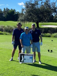 Three golfers in florida behind sign